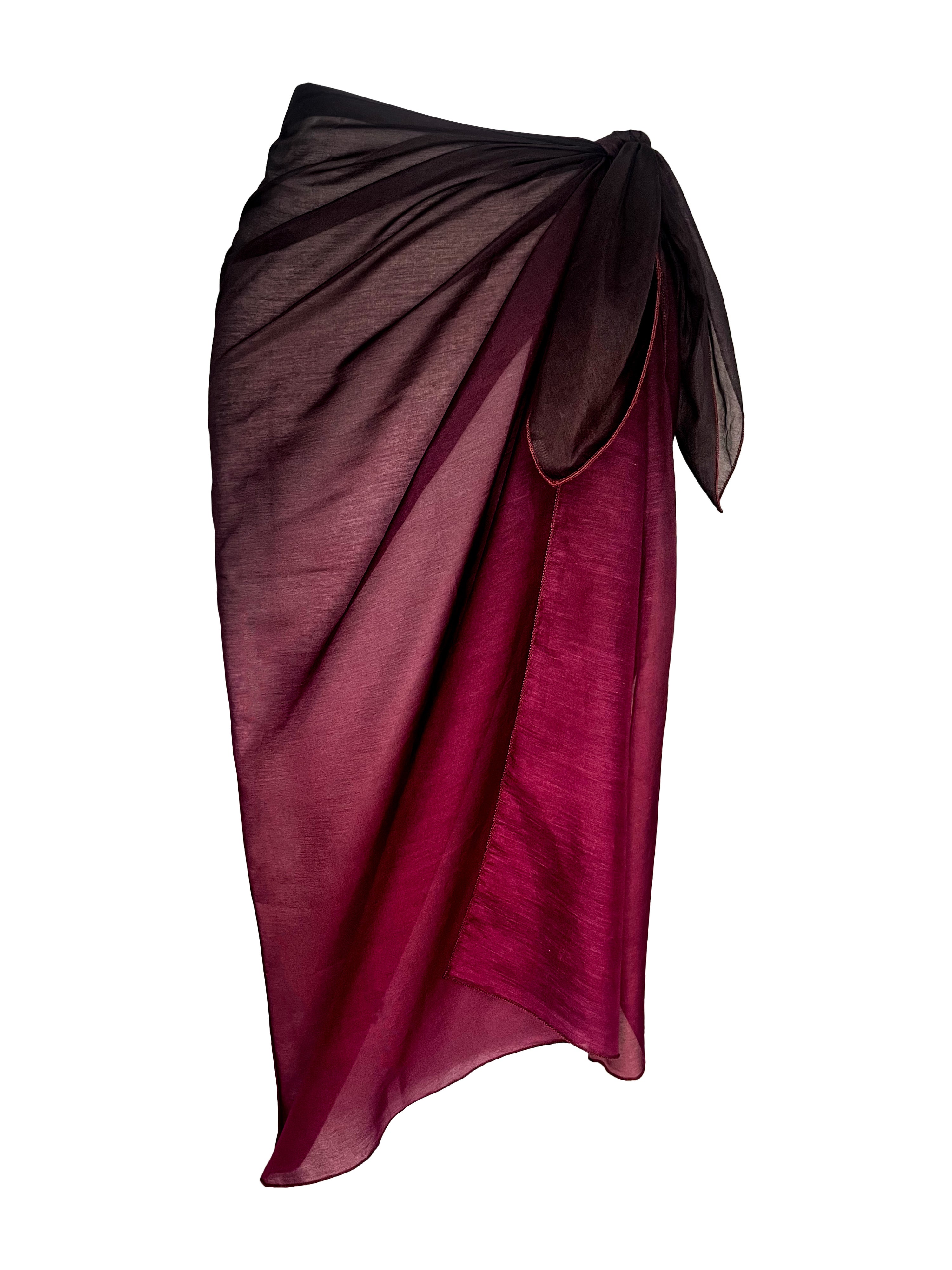 A person standing on a beach wearing a purple silk sarong draped around the waist.