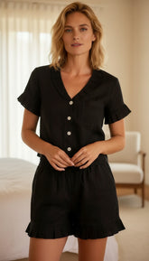 Woman wearing a black romper with buttons in a room setting